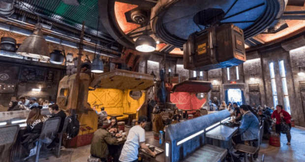 Guests enjoy intergalactic dining amid industrial decor, neon booths, and atmospheric lighting at Galaxy’s Edge in Disneyland Resort.