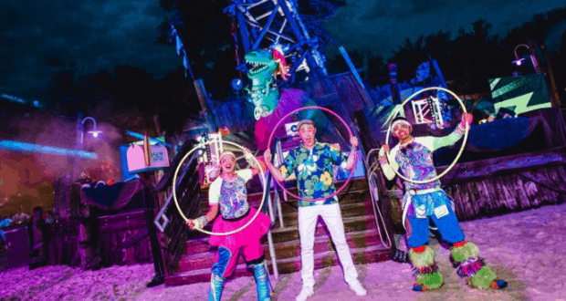 Hula hoop artists light up H2O Glow Nights at Walt Disney World, dazzling guests in vibrant costumes beneath neon lights.