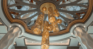 A lavish gold chandelier glows beneath a domed ceiling, echoing the grand, reimagined style of Disney’s Coronado Springs Resort.