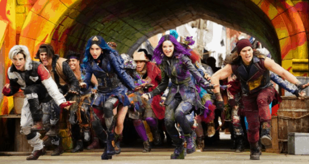Excited teens in vibrant costumes dash from a glowing tunnel at Disney Springs' lively DescenDANCE Party.