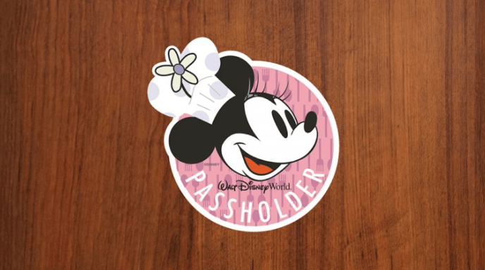 Minnie Mouse in a chef hat on a "Walt Disney World Passholder" sticker, perfect for park fans, on a wooden table.
