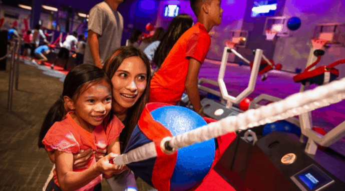 Guests enjoy friendly competition at the NBA Experience, smiling as they shoot hoops together in this bustling, energetic venue.