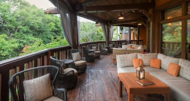 Chill on a wooden lounge deck with plush sofas, lush trees, and glowing roof lights—Animal Kingdom relaxation at its finest.
