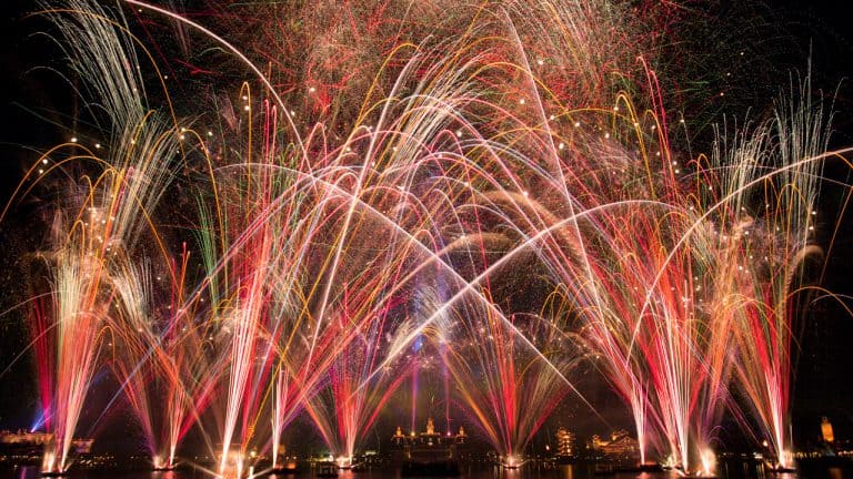 Dazzling fireworks explode over Epcot’s skyline, their colors mirrored on the lagoon, celebrating Epcot Forever at Disney World.