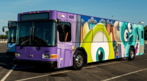 Monsters, Inc.-themed purple Disney bus parked under sunny skies at Walt Disney World, showcasing the resort’s playful fleet.