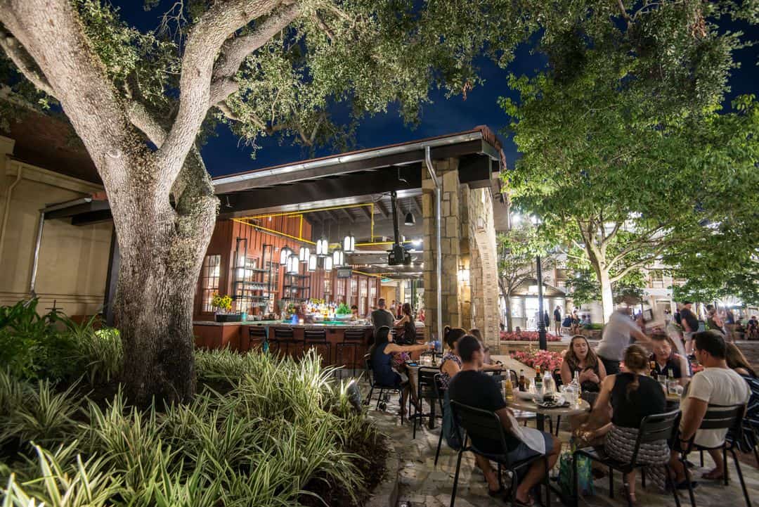 Guests savor Italian cuisine on Terralina’s patio, surrounded by twinkling lights and greenery in Disney Springs’ lively nightlife.