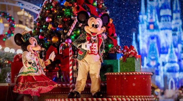 Mickey and Minnie Mouse dazzle in festive outfits beside a decorated Christmas tree at the Ultimate Disney Christmas celebration.