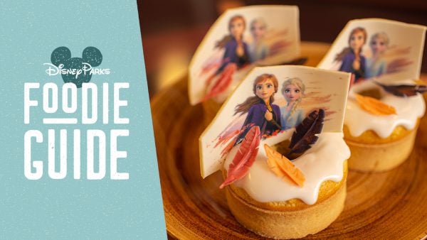 Frozen 2-themed cupcakes with character toppers and feathers displayed beside the Walt Disney World Foodie Guide sign.