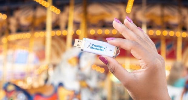 The Memory Maker USB labeled "Vacation Memories" shines in front of a spinning carousel at Walt Disney World.