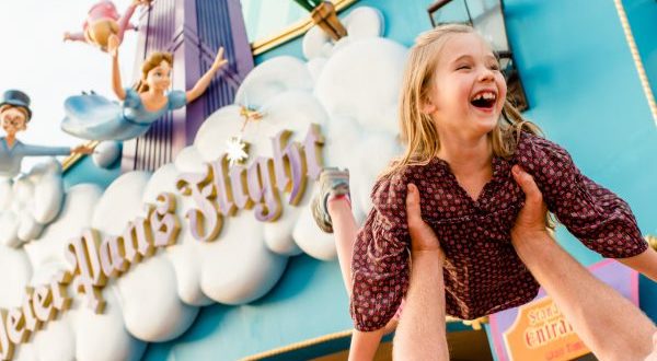 A joyful family moment at Peter Pan’s Flight in Magic Kingdom during Early Morning Magic, with a child lifted in delight.