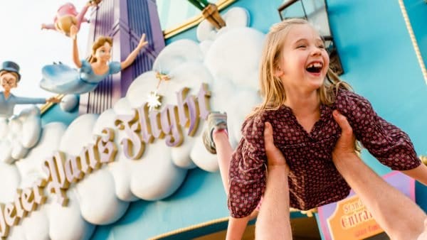 A joyful family moment at Peter Pan’s Flight in Magic Kingdom during Early Morning Magic, with a child lifted in delight.