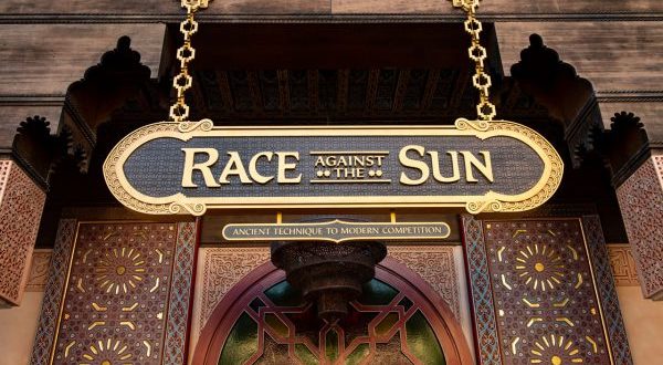 Race Against The Sun" sign with intricate patterns and gold trim stands above an entrance in Epcot’s Morocco Pavilion.