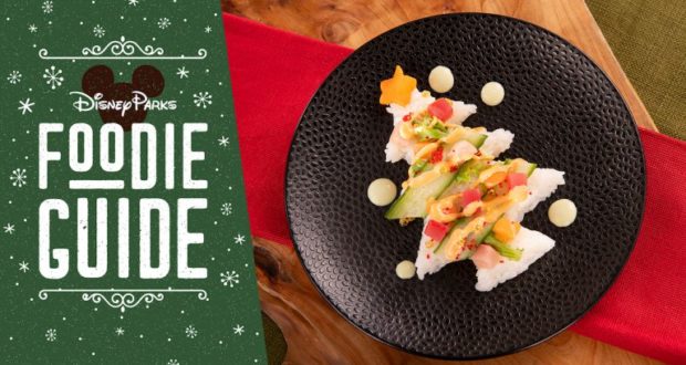 Sushi shaped like a Christmas tree on a black plate sits by the Disney Parks Foodie Guide at Epcot’s 2019 Festival of the Holidays.