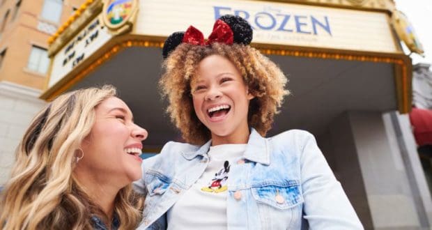 Fans in Mickey ears beam outside a "Frozen 2" theater, enjoying enchanting photo ops at Walt Disney World.