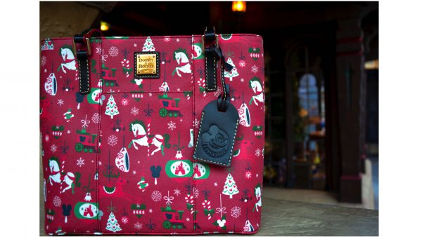 Festive Dooney & Bourke tote with rocking horses, trees, ornaments, and a Mickey Mouse tag—ideal for Disney Parks visitors.