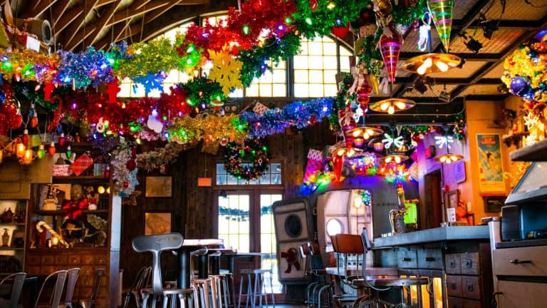 Jock Lindsey’s Holiday Bar at Disney Springs glows with festive lights, garlands, and ornaments throughout Walt Disney World.