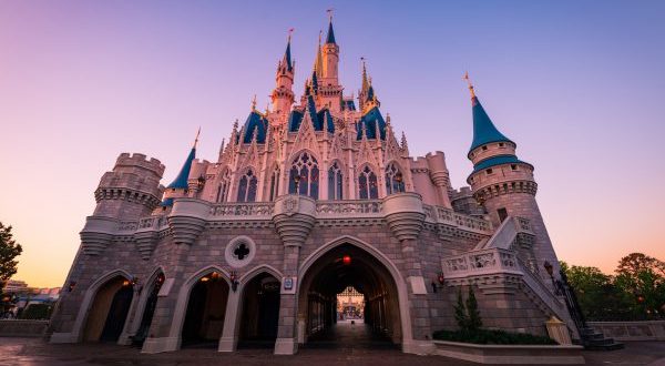 Cinderella Castle at Walt Disney World Resort glowing at sunrise, with empty Main Street and a brilliant clear sky overhead.