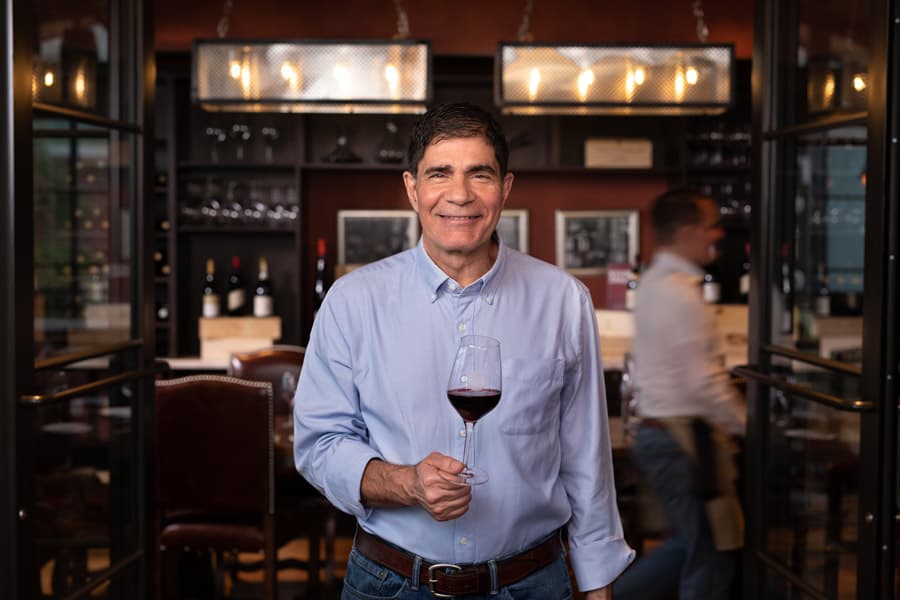 A happy guest in a blue shirt enjoys red wine at an upscale Disney Springs restaurant, snapped in December 2019 for Foodie News.