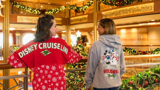 Guests aboard a Disney Cruise Line ship sport exclusive holiday sweaters, smiling and showing off festive new merchandise.