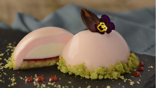Decadent pink mousse dessert with chocolate leaf and edible flower, sliced to reveal creamy layers—a star at Epcot’s 2020 Arts Fest.