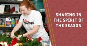 A cheerful Disney Cast Member adds festive touches to a holiday wreath near the words, "Sharing in the spirit of the season.