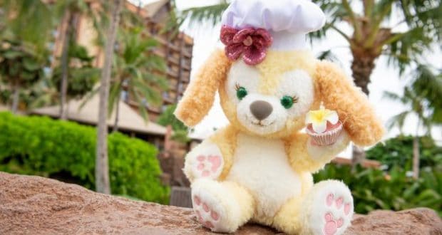 CookieAnn from Duffy and Friends, in a chef hat with a cupcake, poses by palm trees at Aulani, A Disney Resort & Spa.