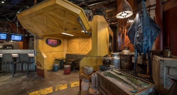 Docking Bay 7–inspired sci-fi restaurant with yellow booths, metal barrels, and alien decor delivers an intergalactic experience.