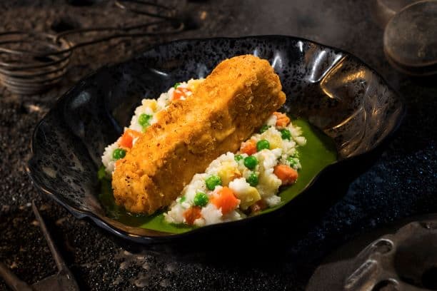 Crispy fried fish atop vibrant veggies and green sauce, plated in a black bowl—just like at Docking Bay 7 in Galaxy’s Edge.