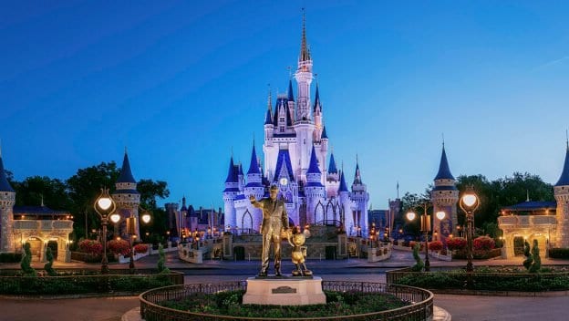 Cinderella Castle glowing at dusk, with Walt Disney and Mickey Mouse statue in front during DisneyParksLIVE’s Super Bowl celebration.