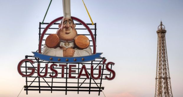 Gusteau’s neon chef sign lights up the evening at Epcot’s France Pavilion, with the Eiffel Tower in the background.