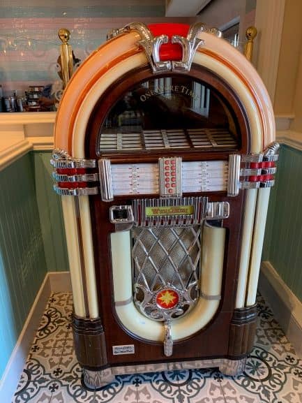 A classic jukebox with gleaming chrome and vibrant lights brightens the retro tile floor at Beaches & Cream Soda Shop in Disney World.