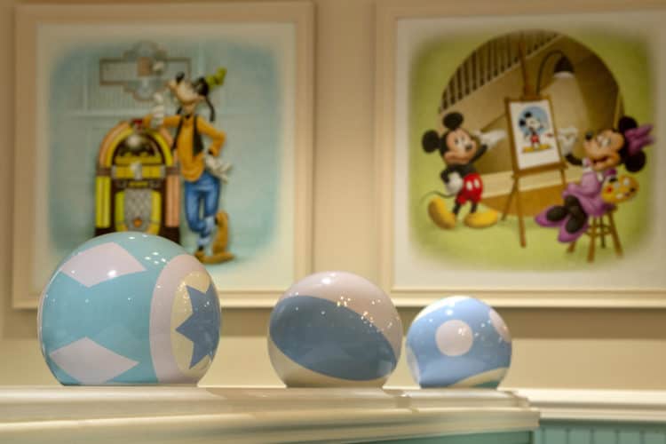 Pastel beach balls on a ledge pop against framed Disney art, capturing the playful vibe of Beaches & Cream at Disney World.