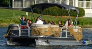 Families and kids cruise the lake on a festively netted pontoon, captivated by Mermaid School stories under the sun.