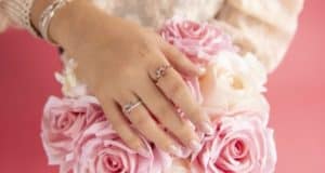A ring-adorned hand rests on a bouquet of pink and white roses, evoking the dreamy romance of Disney Springs in a magical setting.