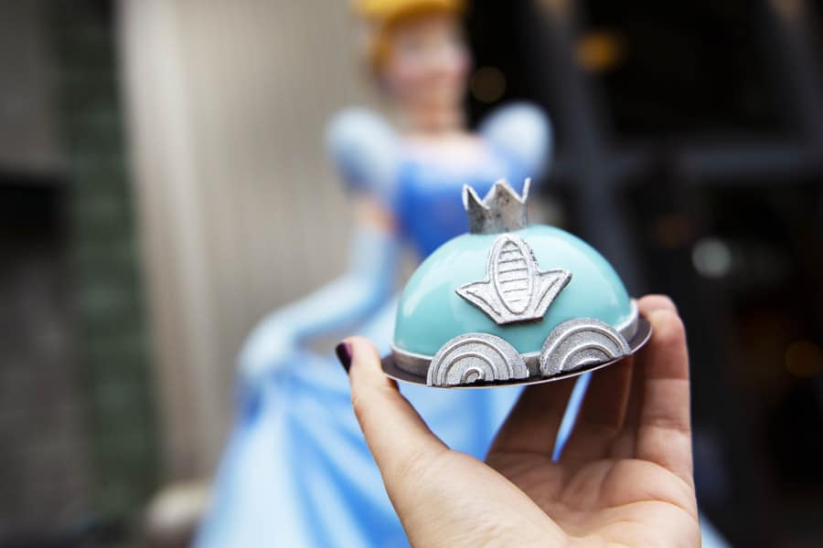 Cinderella’s blue carriage treat is held up with her statue in the background, captured at Walt Disney World.