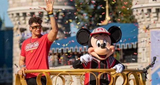 Mickey Mouse waves alongside a guest on a confetti-filled parade float at Disney World, channeling championship celebration energy.