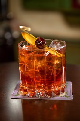 A Disney Wonder cocktail on ice, topped with orange peel and cherry, ready for guests to enjoy as part of the cruise’s magical experience.