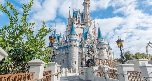 Cinderella Castle with blue spires shines above Disney World, viewed from a lantern-lit bridge—pure theme park magic awaits.