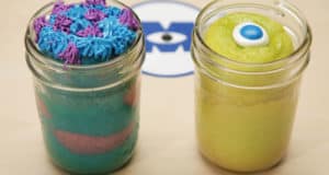Monsters, Inc.-themed cake jars featuring Mike & Sulley: blue with purple frosting, and yellow with a single eye at Disney Parks.