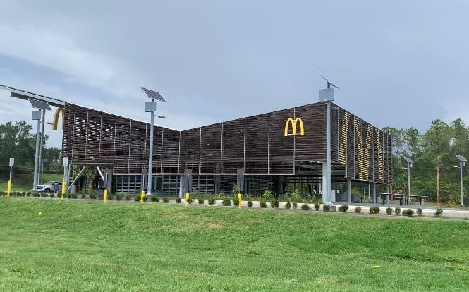 Eco-friendly McDonald’s with solar panels and a striking wooden design, set amid greenery, evoking the Disney World location.