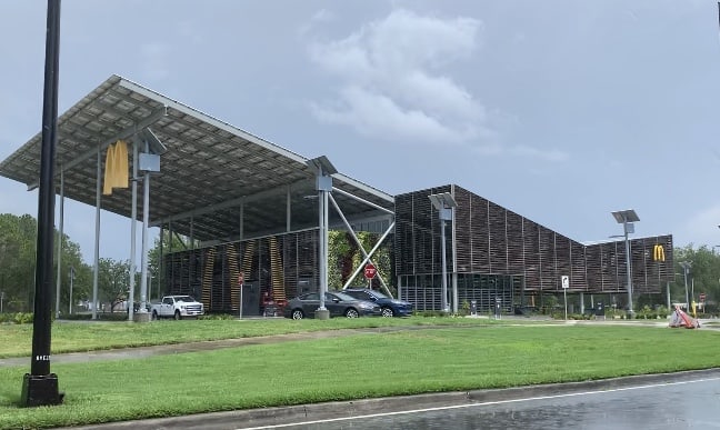 Futuristic, eco-friendly McDonald’s at Walt Disney World, featuring solar panels and welcoming guests under a dramatic sky.