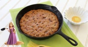 An Allergy Friendly Frying Pan Cookie in a skillet on a green mat, with Rapunzel and a Tangled flower dish evoking Disney magic.