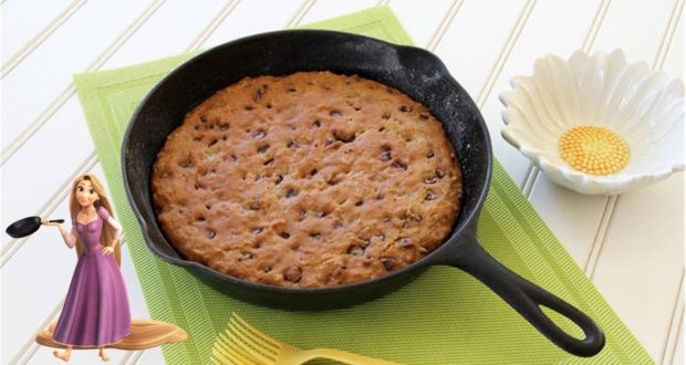 An Allergy Friendly Frying Pan Cookie in a skillet on a green mat, with Rapunzel and a Tangled flower dish evoking Disney magic.