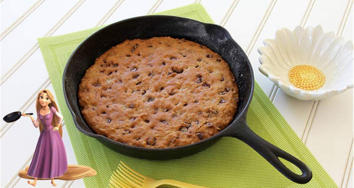 An Allergy Friendly Frying Pan Cookie in a skillet on a green mat, with Rapunzel and a Tangled flower dish evoking Disney magic.