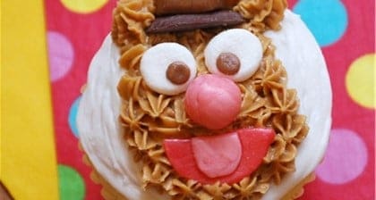 Fozzie Bear cupcake with frosted face and candy features, served on a playful backdrop—ideal for Muppet fans at Disney parks!.