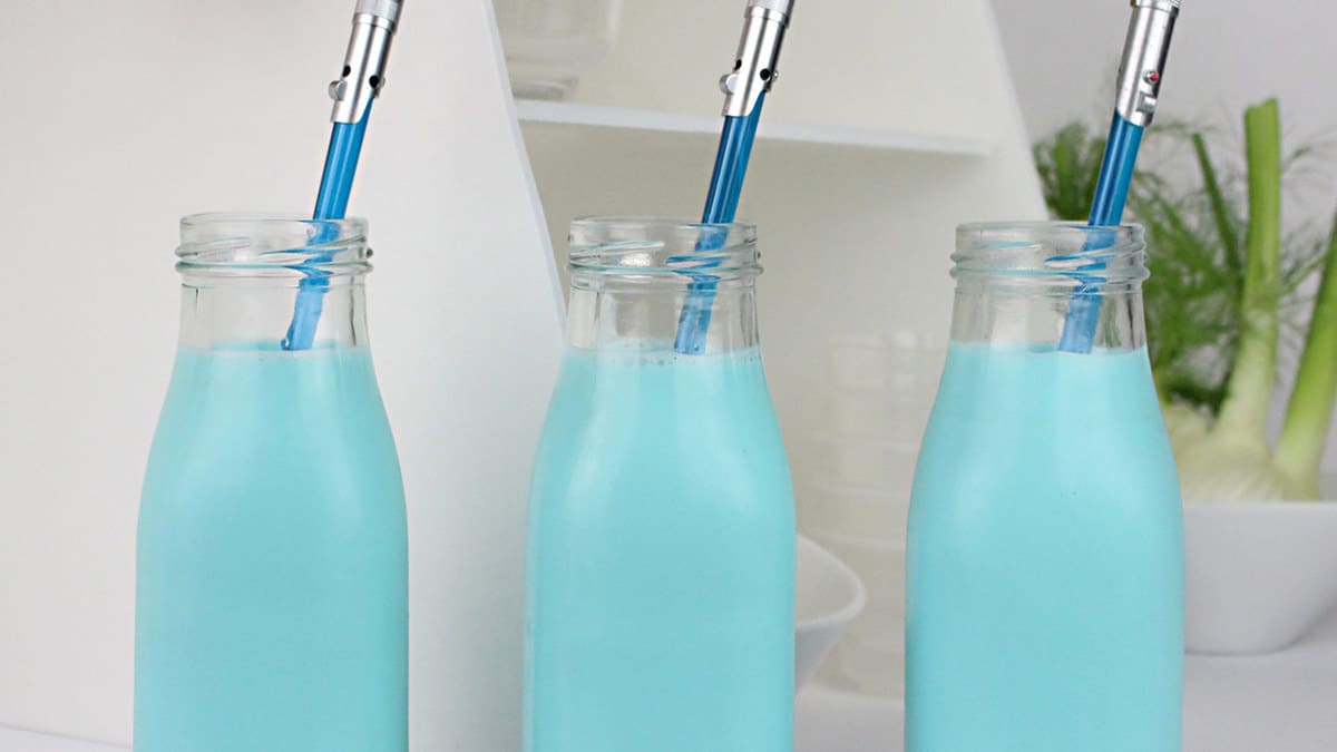 Three glass bottles of blue milk with matching straws, ready for Galaxy’s Edge fans on a crisp white counter—Star Wars magic awaits!.