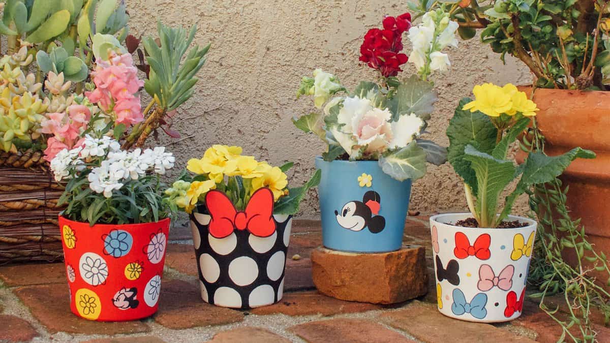 Minnie Mouse-themed flower pots burst with color and blooms, creating a cheerful Disney-inspired patio garden near lush greenery.