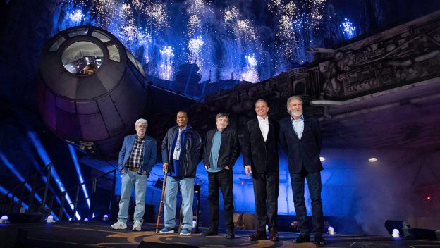 Guests pose in front of the Millennium Falcon at Galaxy’s Edge as fireworks illuminate the night sky at Disneyland Resort.
