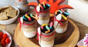 Colorful, five-layered Ice Cream Parfaits with gummy worms and spoons on a wooden tray, perfect for a Lion King-themed snack.