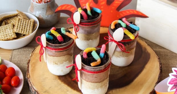 Colorful, five-layered Ice Cream Parfaits with gummy worms and spoons on a wooden tray, perfect for a Lion King-themed snack.